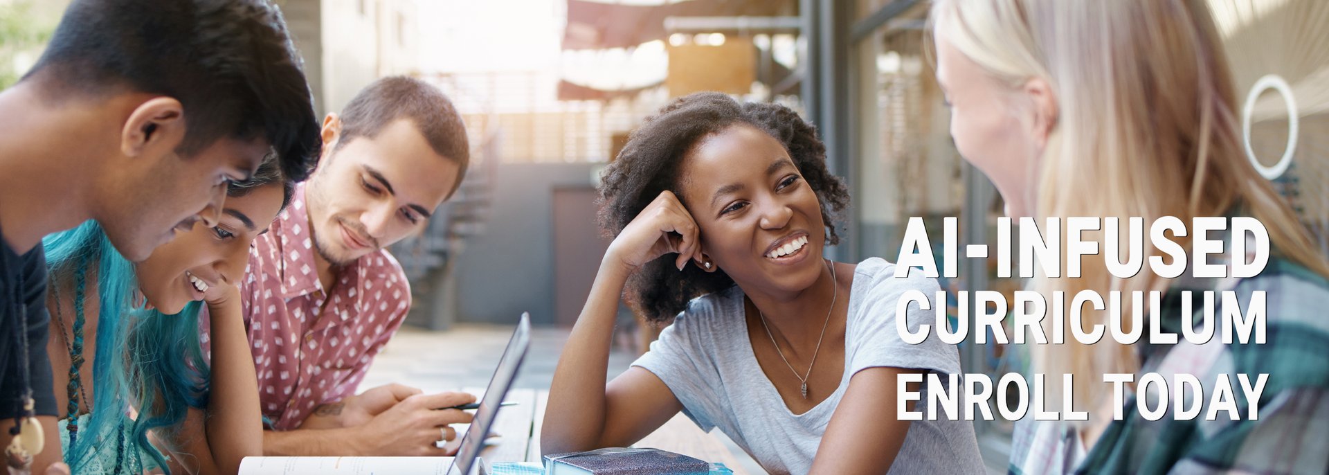 Young adults studying together at a table with books and laptops