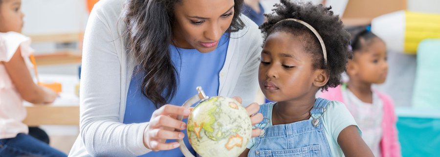 teacher showing young child a globe of the world