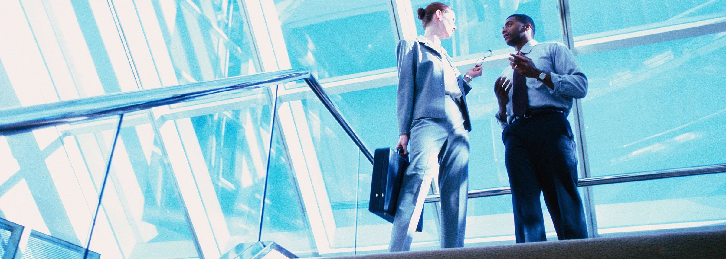 professional woman and man talking at the top of a staircase